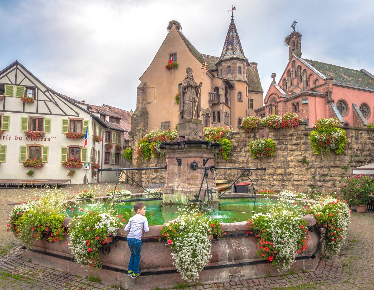 Flower-filled fountain and half-timbered houses in Eguisheim, Alsace